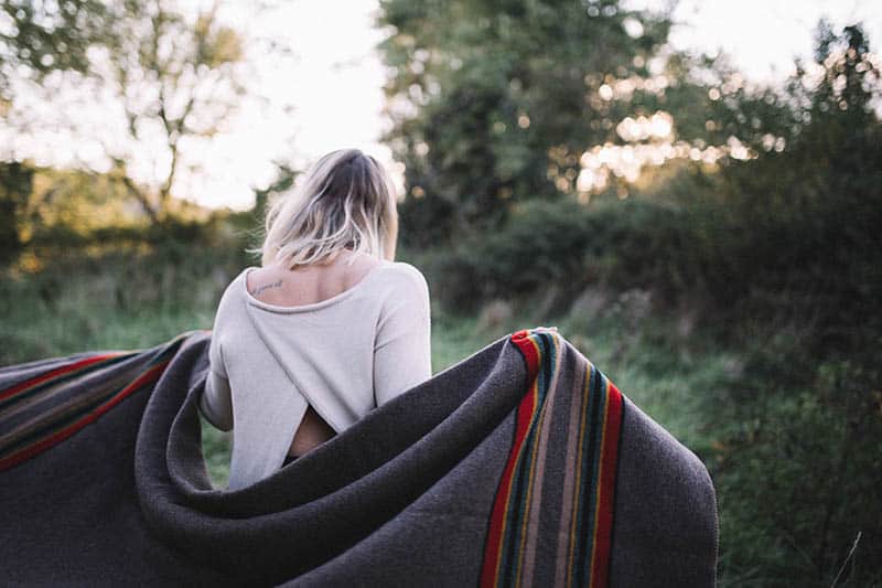 vista posteriore di una donna che tiene una coperta all'esterno