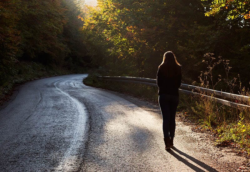 vista trasera de mujer caminando sola por la carretera