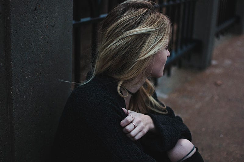 blonde woman sitting on street