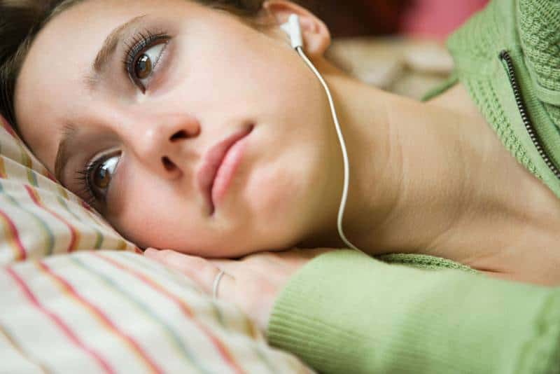 close up photo of woman listening sad music with earphones