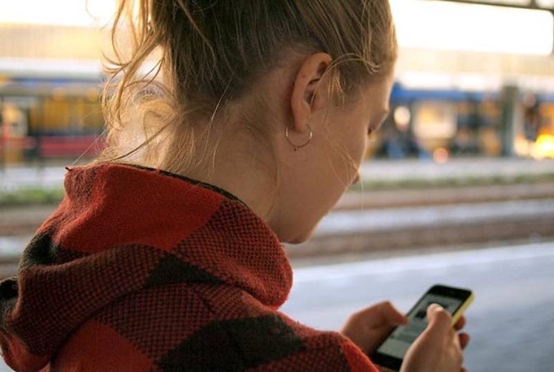 foto de cerca de una mujer escribiendo en su teléfono mientras camina