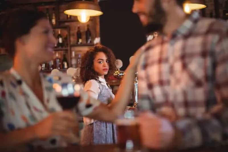 jealous woman looking at man and woman in bar