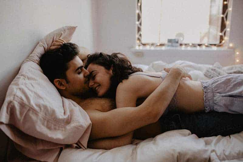 encantadora mujer acostada sobre su novio en la cama