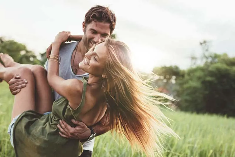 man holds smiling woman in arms