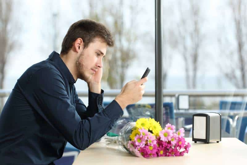 uomo che guarda il telefono infelice