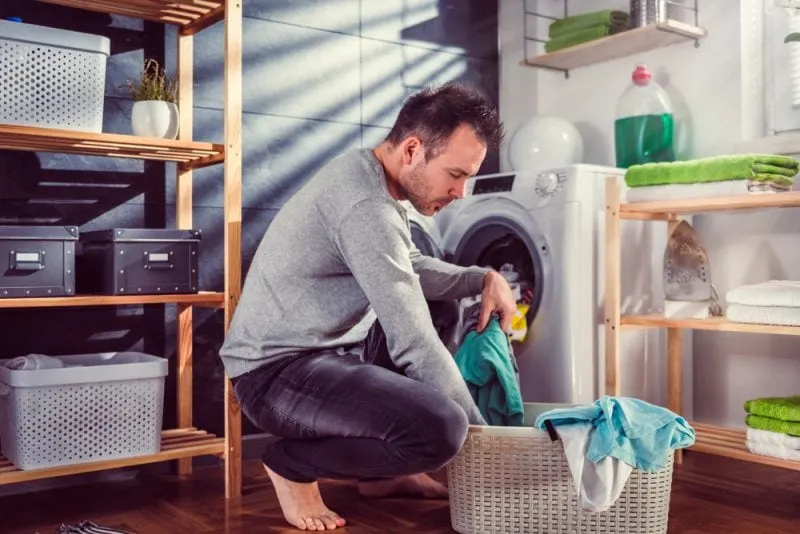 man putting clothes into washing machine