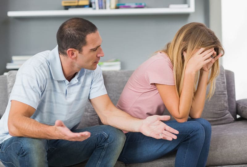 man talking to sad woman on the couch