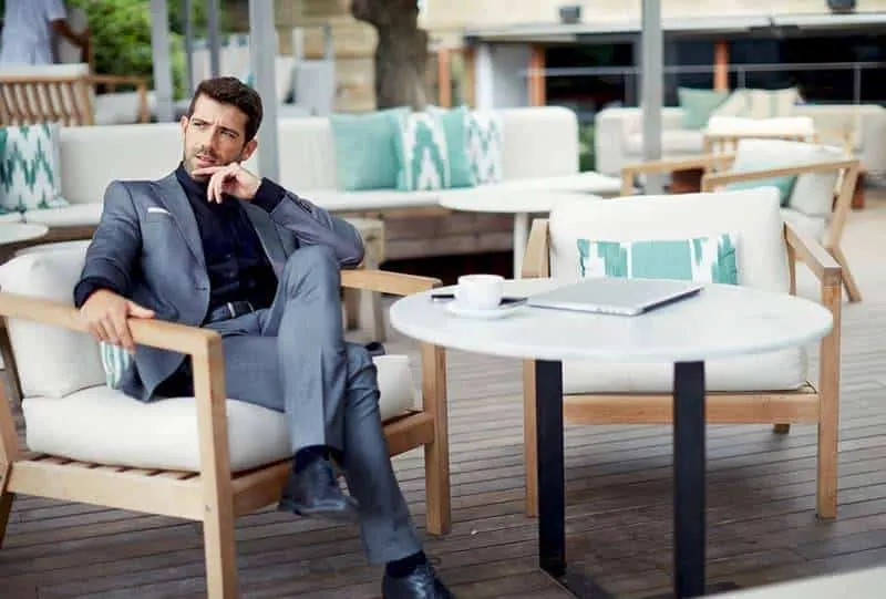 man wearing suit and sitting in outdoor cafe