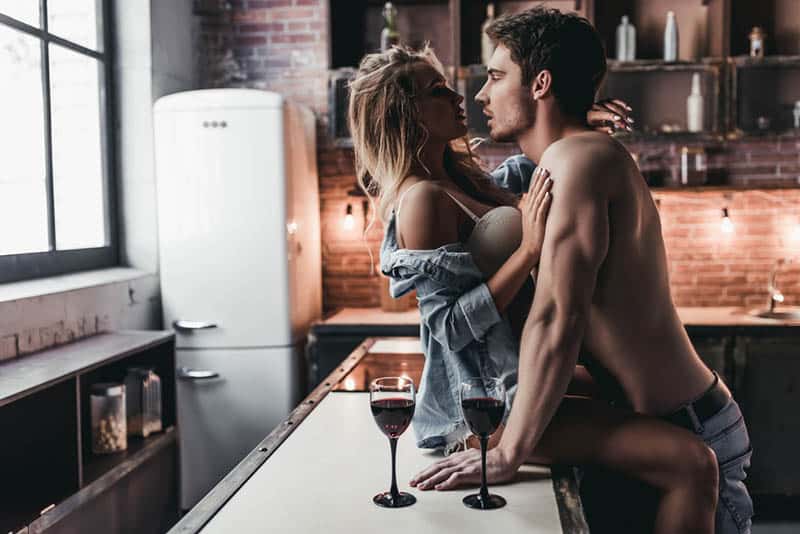 passionate couple in the kitchen with two glasses of wine