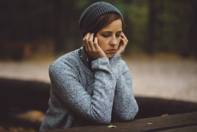 donna triste seduta da sola nella foresta