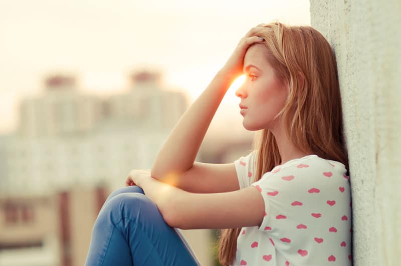 mujer triste sentada en el tejado