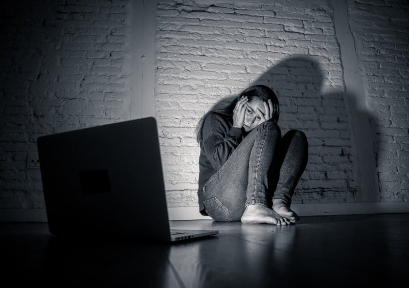 scared woman looking at laptop crying