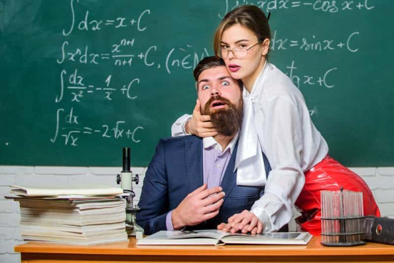 profesora sexy retiene a un hombre con barba en la escuela