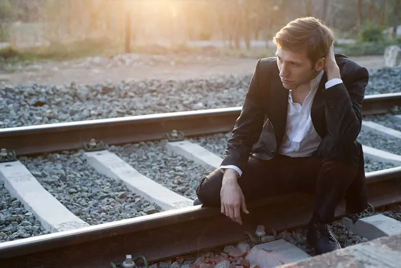Portrait of young man with suit sitting in rail way