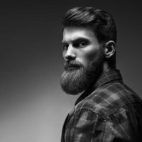 Black and white photo of bearded stylish businessman Handsome confident perfect hairstyle man indoor .