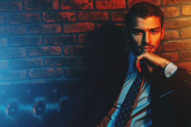 Respetable hombre guapo en traje elegante sentado en apartamentos con interior de lujo clásico. La belleza de los hombres, la moda.