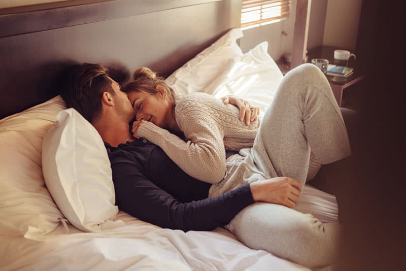 Loving young couple sleeping together in bed. Young man and woman lying together in bedroom.
