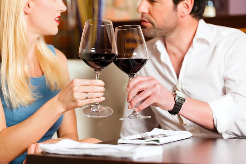 Atractiva pareja joven bebiendo vino tinto en restaurante o bar, podría ser la primera cita