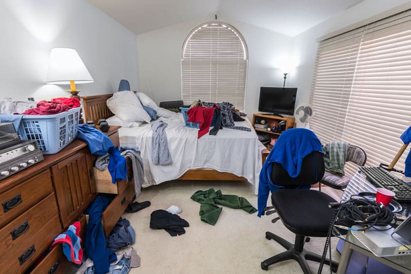 Messy, cluttered teenage boy's bedroom with piles of clothes, music and sports equipment. 