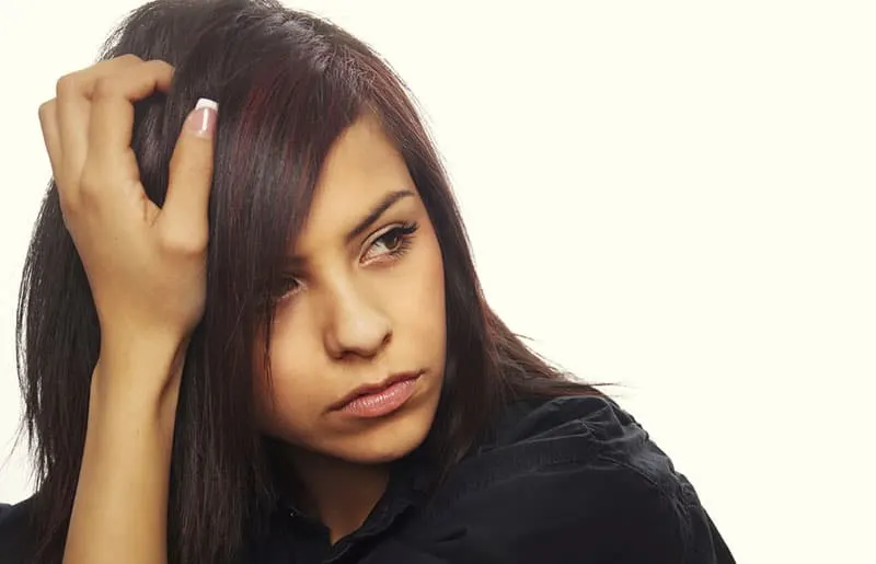 Young woman with serious expression leaning with her hand on hair.