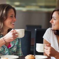 Due studenti sorridenti che bevono una tazza di caffè nella mensa universitaria