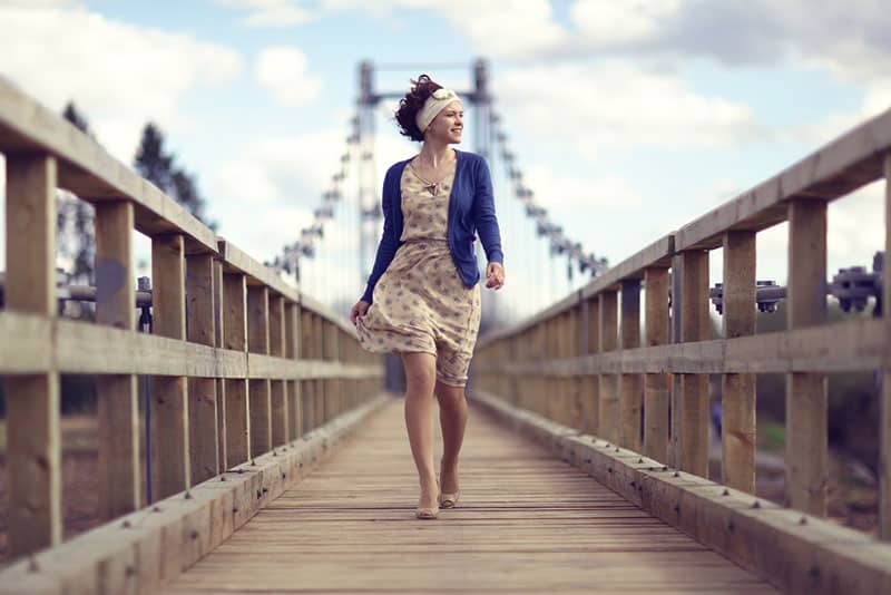 happy girl dress runs over the bridge