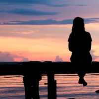 Lonely woman sitting on a wooden bridge sunset.are Lonely. style abstract shadows.silhouette