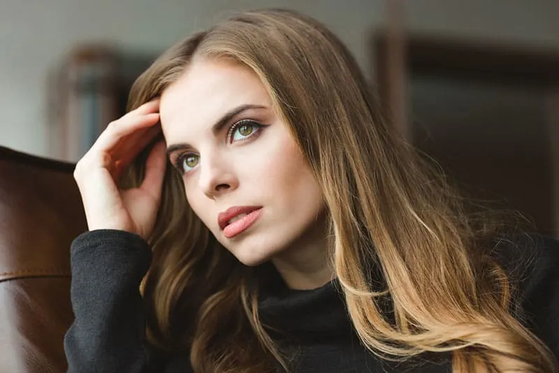 Portrait of attractive thoughtful young woman sitting at home
