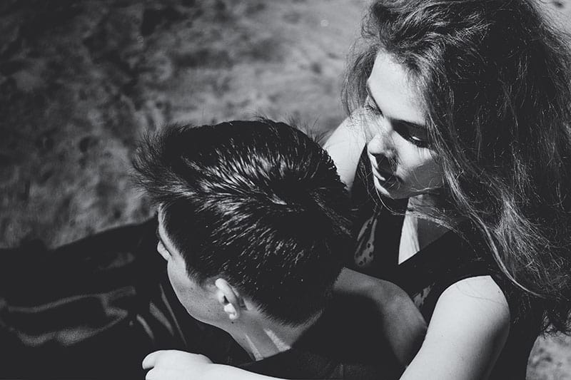 Beautiful couple. Girl whispers something in the ear of young man, black and white portrait