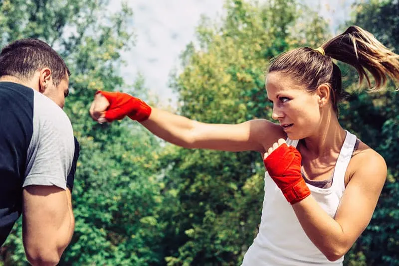 Woman throwing a punch to man on taebo training 