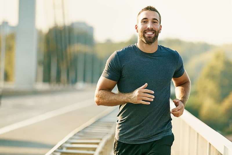 Handsome young man running across the bridge.