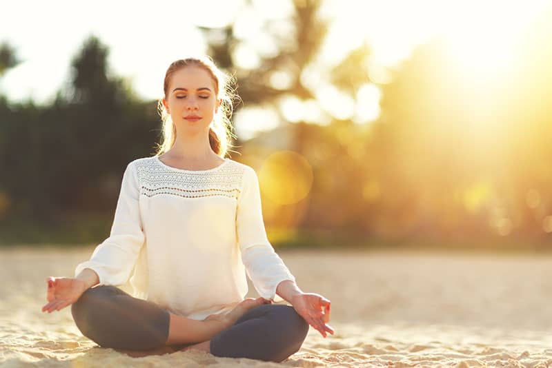 donna pratica yoga e medita nella posizione del loto sulla spiaggia