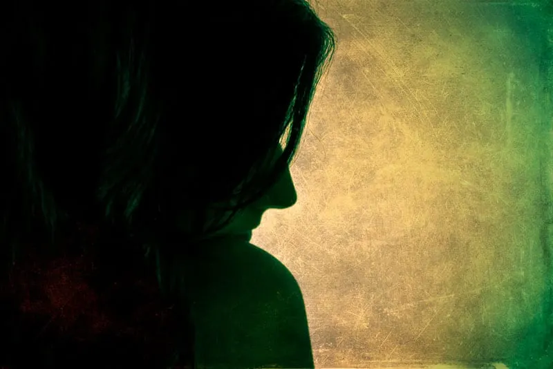 Woman profile silhouette in dark. Green background. Photo