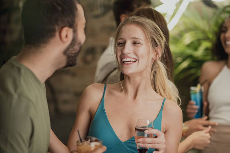 Amigos a socializar durante um cocktail num clube noturno. Estão a rir e a conversar.