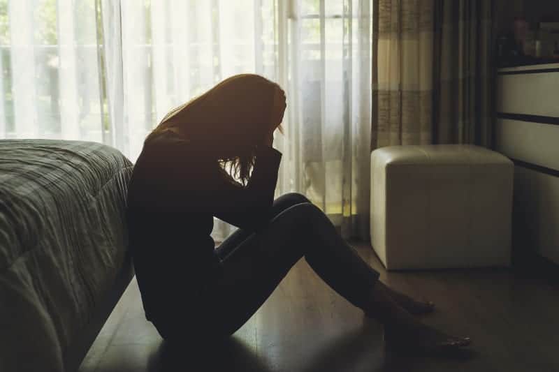 side view of depressed woman sitting on floor