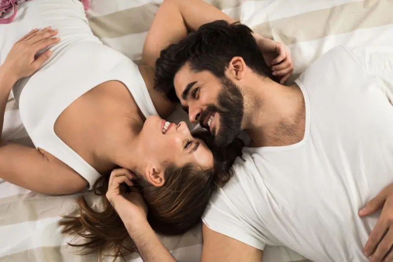 smiling couple lying down in bed