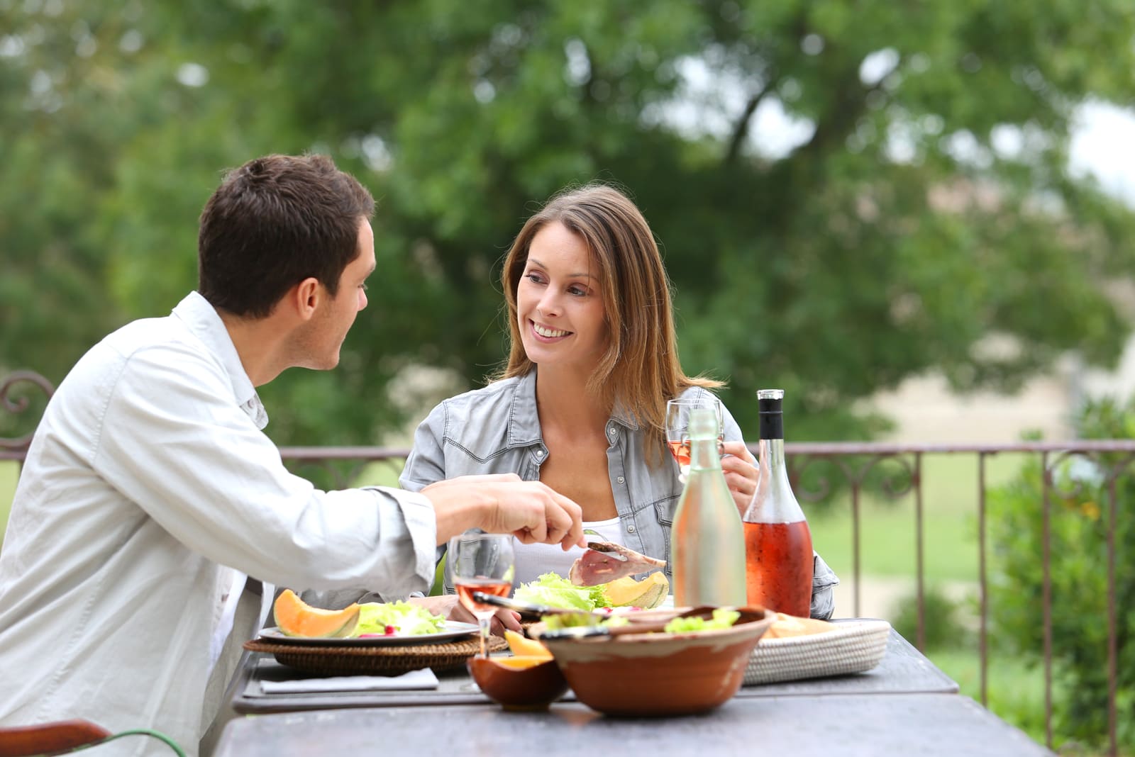 sonriente pareja de enamorados almorzando en la terraza