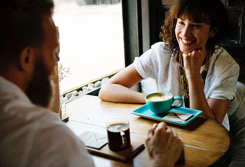mujer sonriente mirando a un hombre en un café
