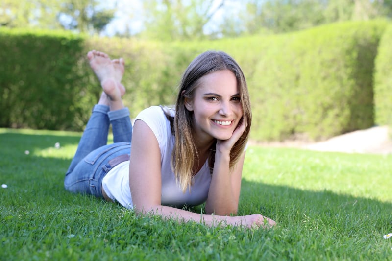 smiling woman lying on grass field