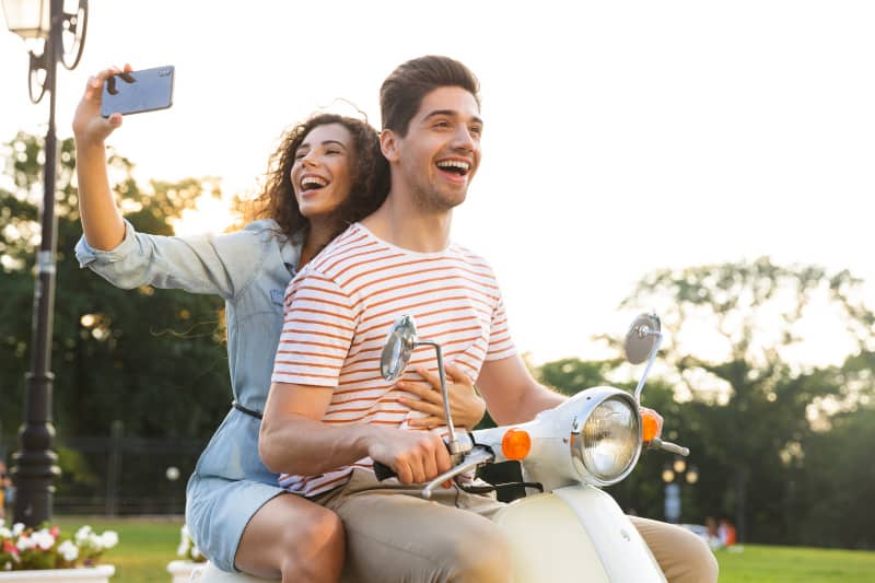 smiling woman taking selfie while ridding with her man