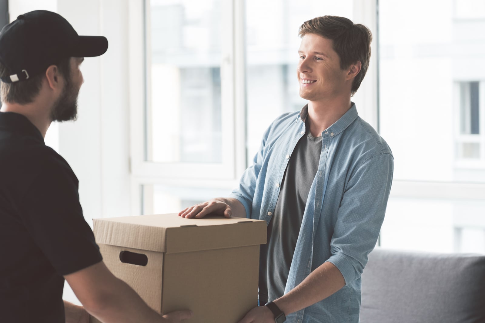 the delivery man hands the package to the smiling man