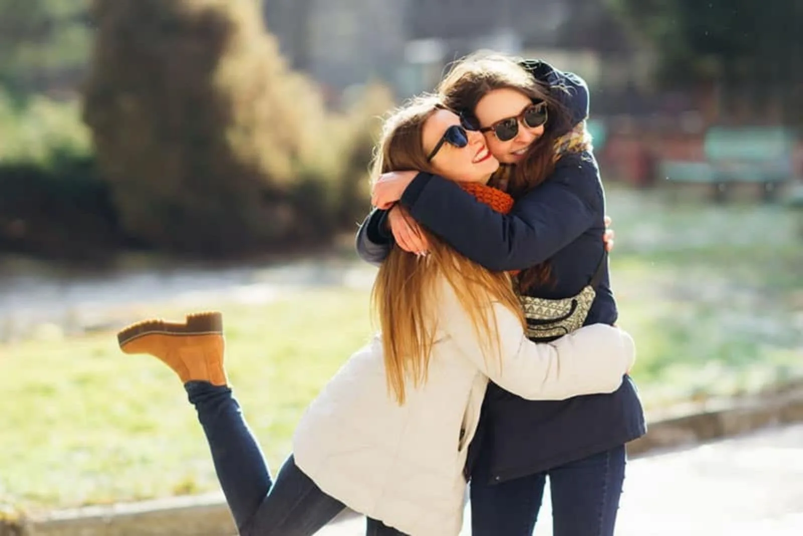 two friends with glasses and long jackets embracing