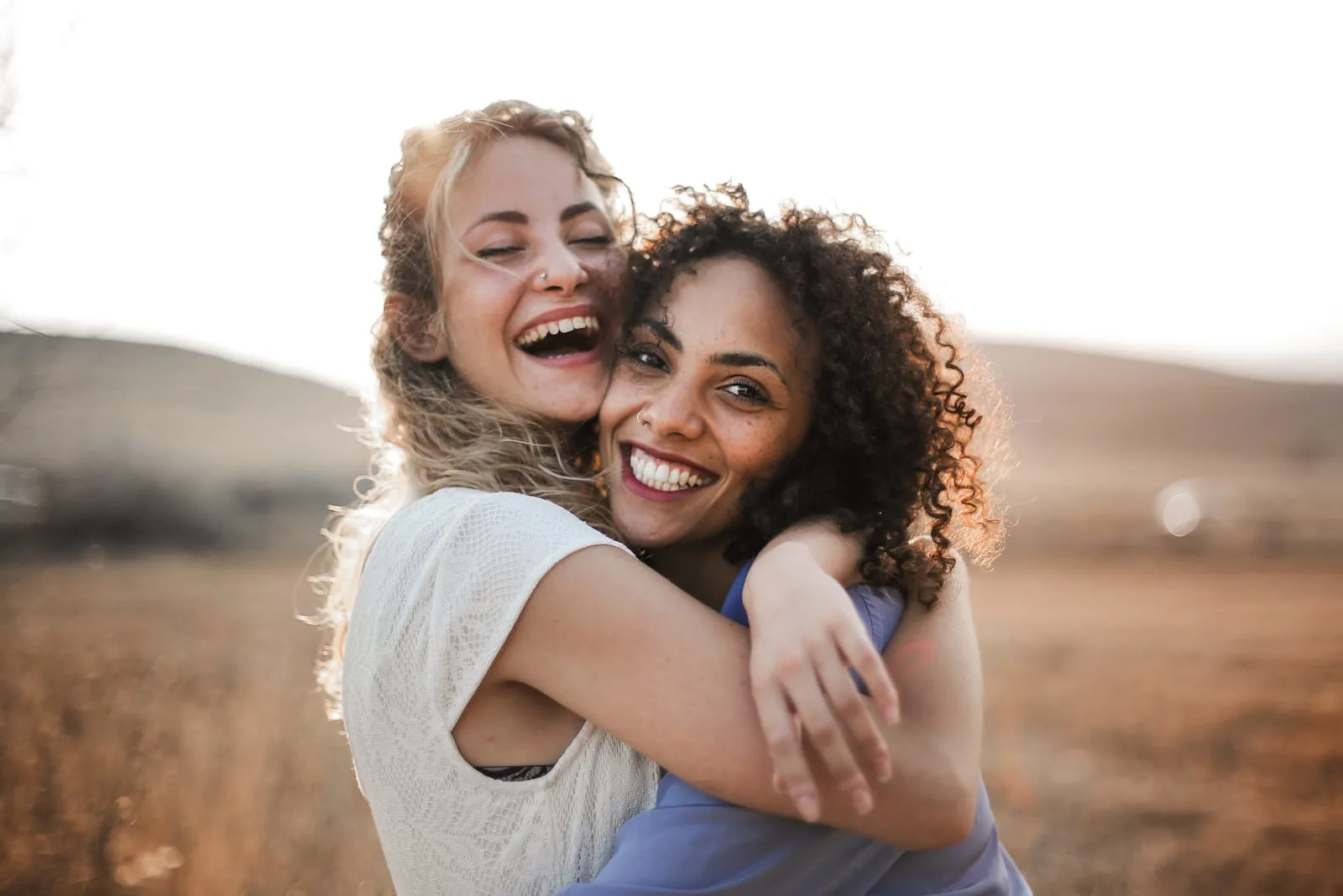 two smiling friends hug