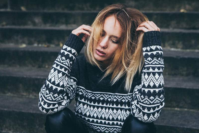 unhappy woman wearing sweatshirt sitting outside