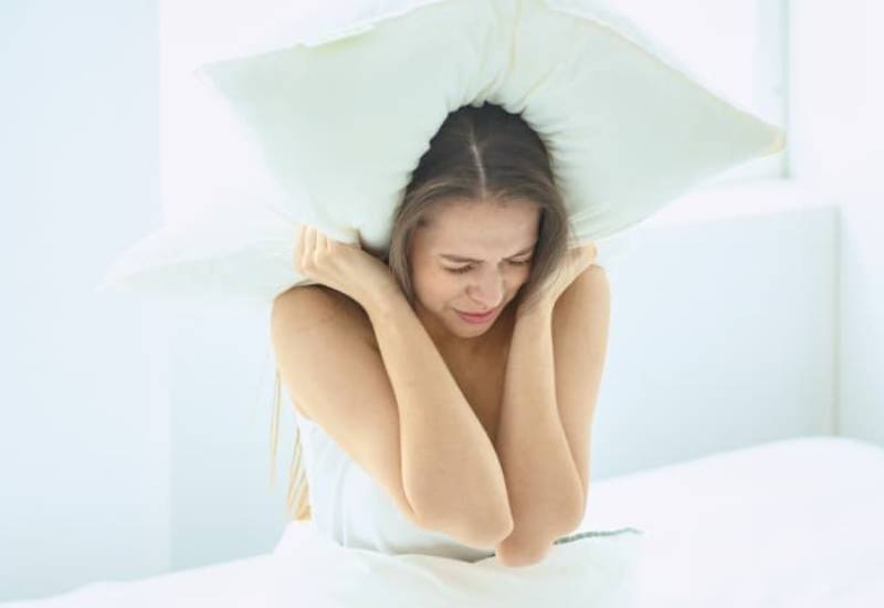 upset woman holding pillow over head