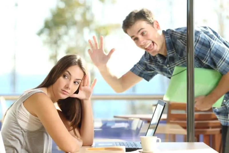 woman ignoring man waving her in a coffee shop