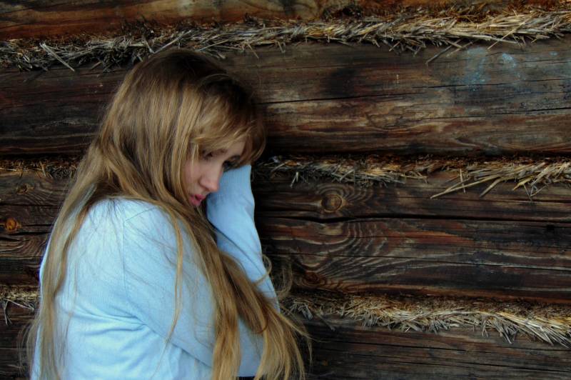 mujer apoyada en una pared de madera negra