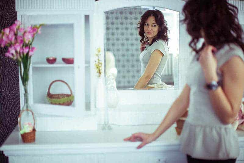 woman looking herself on mirror