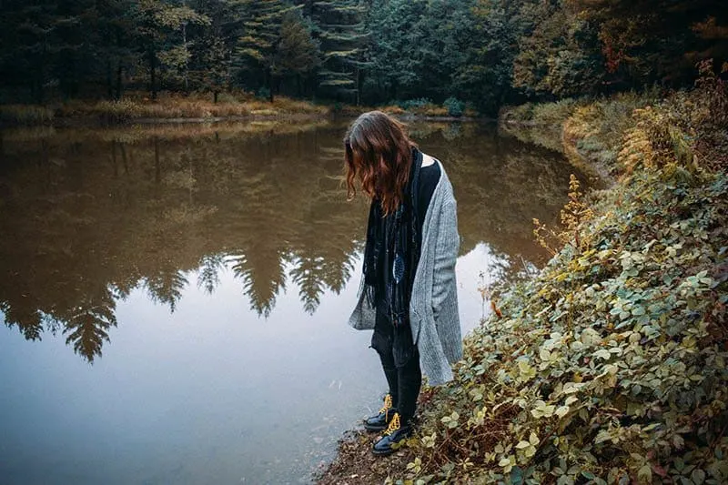 woman looks thoughtful near lake
