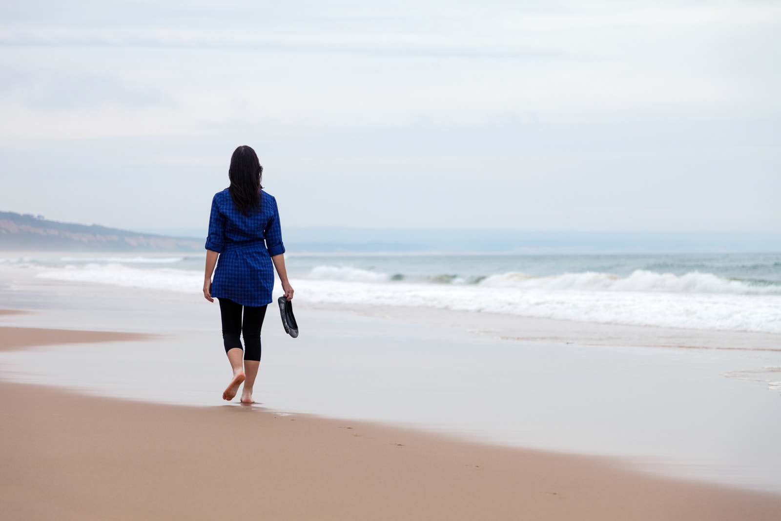 donna che si allontana da sola in una spiaggia deserta